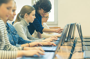 Vergrößerungsansichten für Bild: Nahaufnahme: Eine Lehrerin arbeitet mit Schülerinnen an Laptops