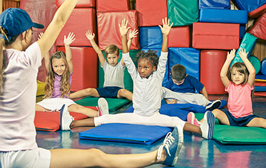 Vergrößerungsansichten für Bild: Foto: Trainerin mit Kindergruppe beim Gymnastiktraining.